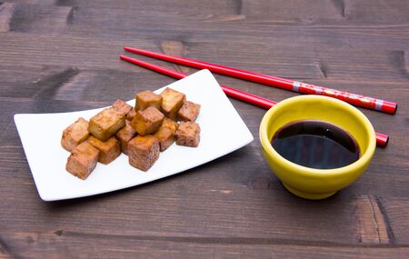 Tofu cubes with soy sauce on wooden tableの写真素材