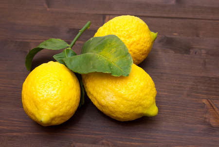 Fresh lemons with leaves on wooden table