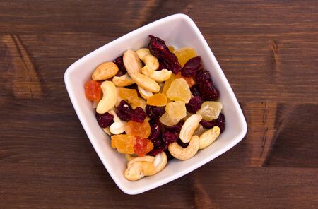 Dried fruits on a square bowl on wooden table seen from aboveの写真素材