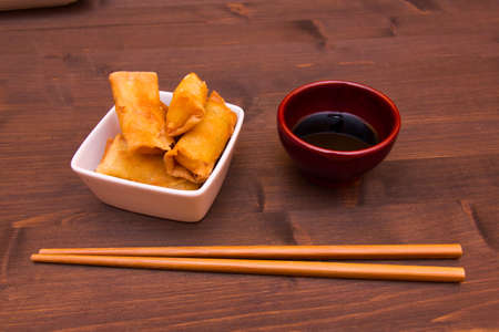 Bowl with spring rolls on a wooden tableの写真素材