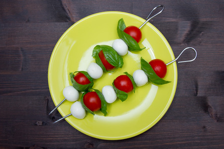 Skewers of mozzarella and tomato on a wooden table seen from aboveの写真素材