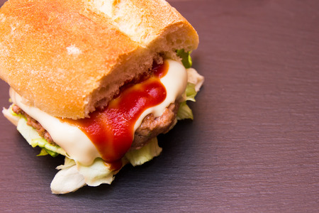Meatball sandwich and cheese on a slate floor seen up close