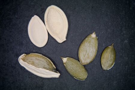 Pumpkin seeds whole and peeled on a slate floorの写真素材