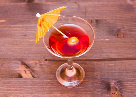 Red cocktail with umbrella on a wooden table seen from aboveの写真素材