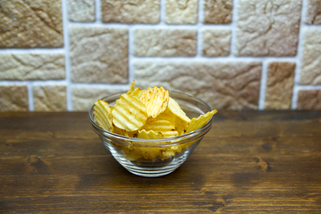 Corrugated chips inside a bowl on a wooden table viewed from aboveの写真素材