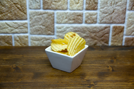 Corrugated chips inside square bowl on a wooden table viewed from aboveの写真素材