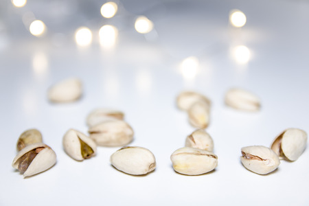 Pistachios on a white background with blurred lights in the backgroundの写真素材