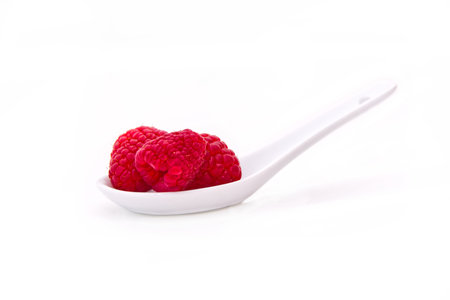 raspberries on spoon on a white backgroundの写真素材