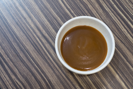 Brown sauce in white cup for seafood and barbecue on wooden backgroundの写真素材