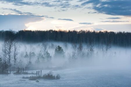evening mist over the lake, the last ice of winter pulls moisture from the warm spring air and creates a beautiful pictureの写真素材