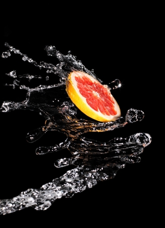 Slice grapefruit in a large drop of clear waterの写真素材
