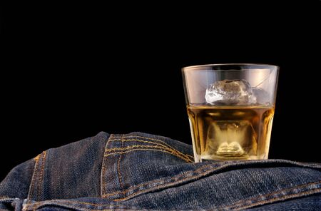 Bourbon on the rocks and denim with black backdropの写真素材