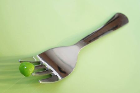 One pea on a fork on a green plateの写真素材