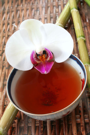 Tea in antique Chinese bowl with bamboo and orchid flowerの写真素材