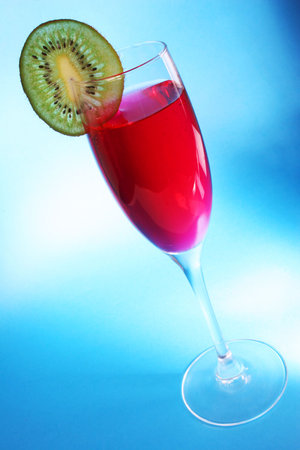 Red cocktail with kiwi slice and blue backgroundの写真素材