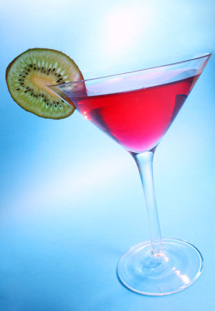 Red cocktail with kiwi garnish with blue backgroundの写真素材