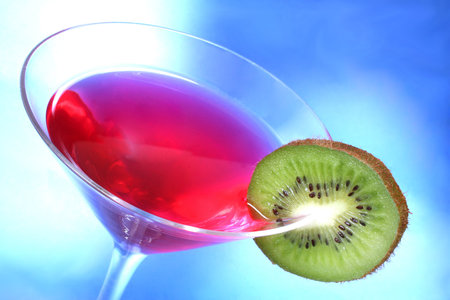 Red cocktail with kiwi garnish and blue light backgroundの写真素材