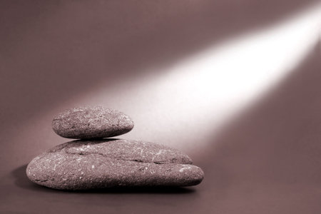 Two blanaced pebbles with a bean of light shining on themの写真素材