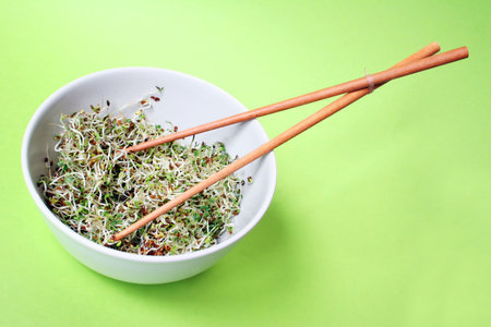 Fresh spouts in bowl with chopsticks and green background
