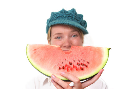 Woman smiling from behind slice of watermelonの写真素材