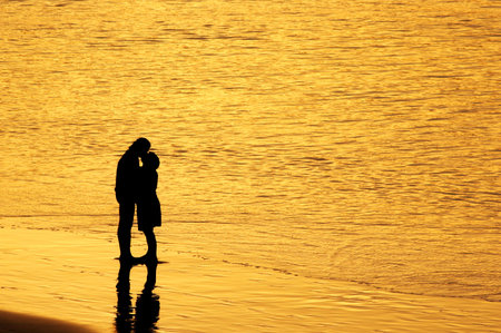 Couple kissing at sunset on the beachの写真素材