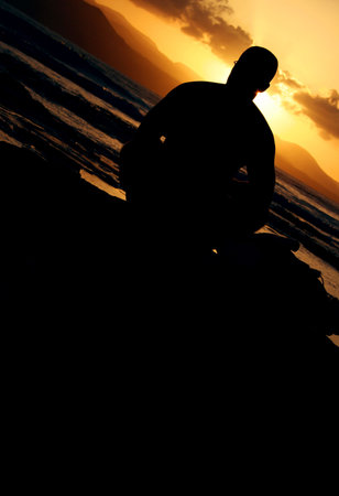 Human figure sitting on the shore at sunsetの写真素材