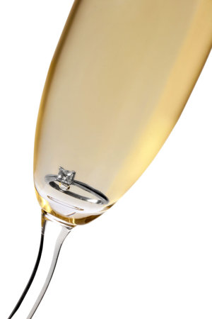 Champagne glass with diamond engagement ring in the bottomの写真素材