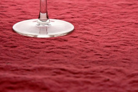 Base of wine glass on rough red table clothの写真素材
