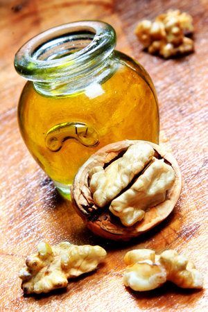 Vintage jar of golden oil with walnuts and wooden backgroundの写真素材