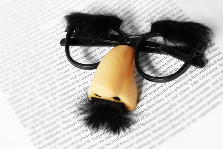 Comedy face mask on page of textの写真素材