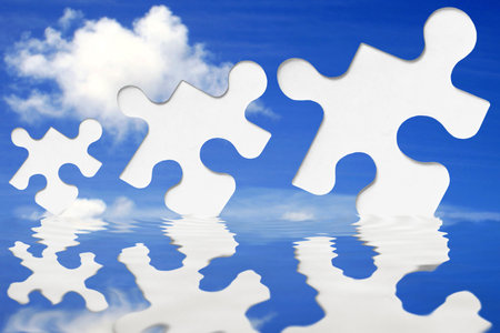 White jigsaw pieces with blue sky and waterの写真素材