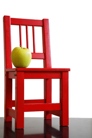 Red school chair and green apple with white backgroundの写真素材
