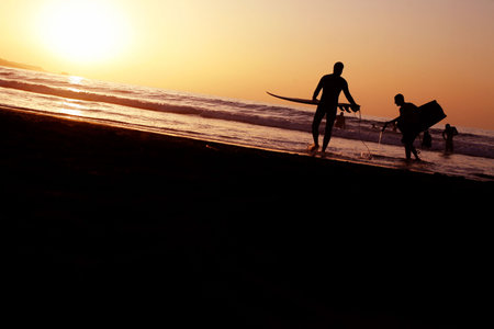 Surfers going into the water at sunset