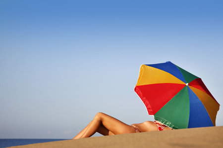 Pretty woman under parasol on the beach