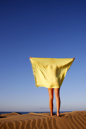 Woman in sand dunes at dawn with sarongの写真素材