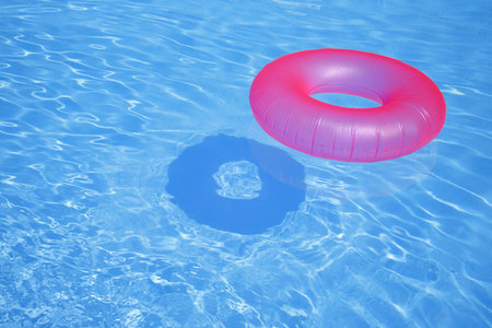 Pink inflatable ring in blue swimming pool