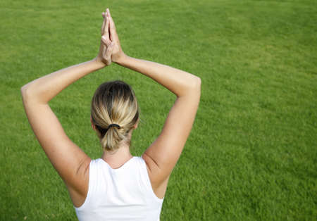 Woman in white in yoga position with green backgroundの写真素材
