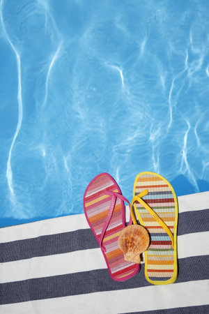 Odd summer shoes by pool with seashell