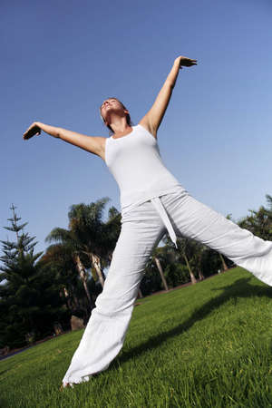 Woman in white in yoga position with blue skyの写真素材