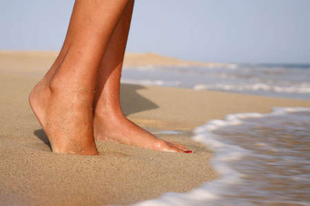 Woman standing on a golden beach with waves at her feet