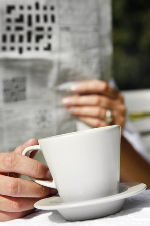 Woman reading the newspaper and drinking coffeeの写真素材