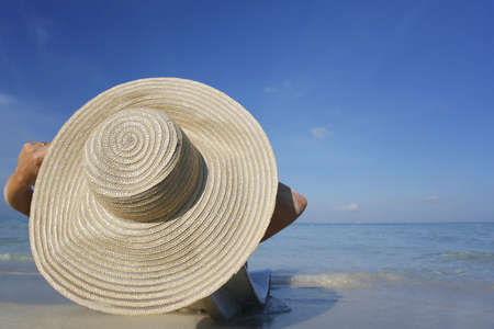 One of a large series. Pretty girl in big straw hat on a tropical beach.の写真素材