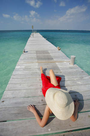 One of a large series. Woman in red bikini sunbathing on a tropical jettyの写真素材
