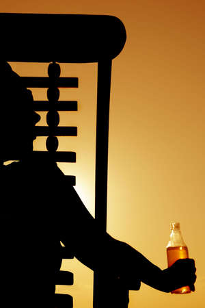 Woman drinking beer in a deckchair at sunsetの写真素材