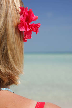 One of a large series. Woman sitting on a beach with a flower behind her ear.の写真素材