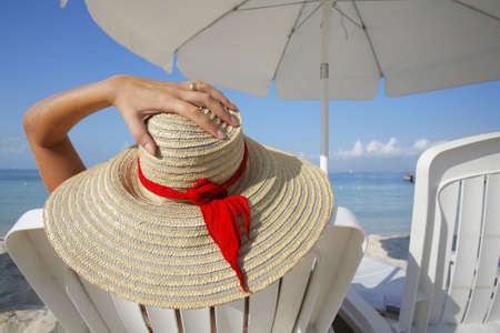 Woman sunbathing on a lounger under a white parasolの写真素材