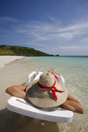 Nice vacation picture with woman sitting on a lounger in pretty tropical waterの写真素材