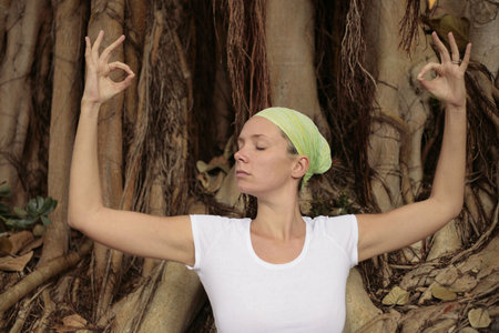 Woman meditating in front of Bodhi Tree rootsの写真素材