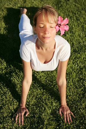 Woman in white meditating on a green lawnの写真素材