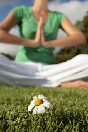 Woman Meditating with Blue Sky and Daisiesの写真素材
